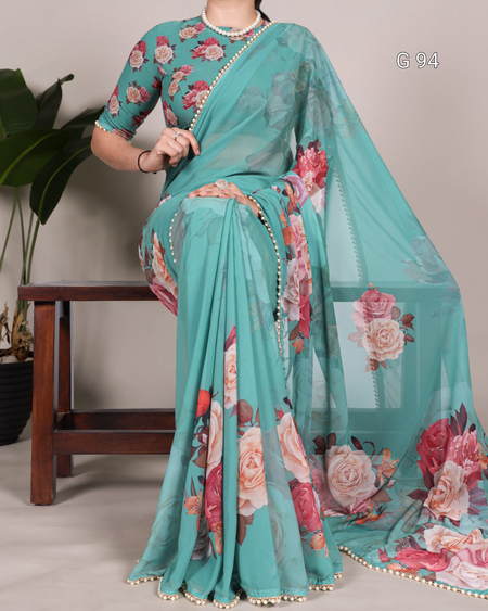 Teal saree with floral patterns draped over a person, sitting on a wooden stool.