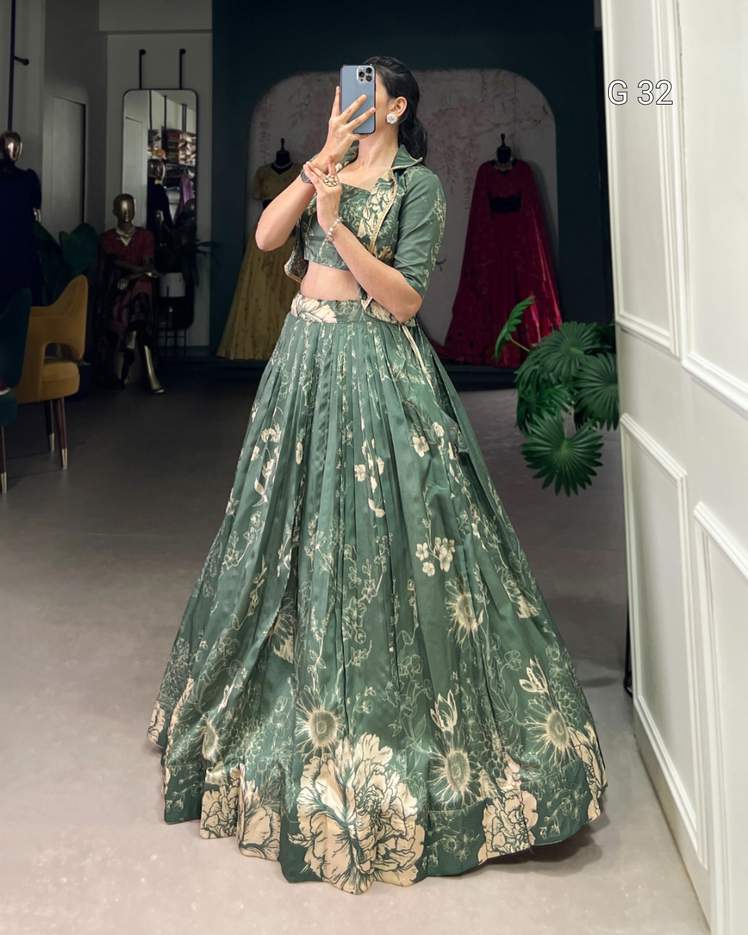 Woman wearing a green floral dress taking a mirror selfie in a room.