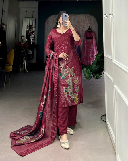 Woman wearing a maroon embroidered traditional outfit in a room.