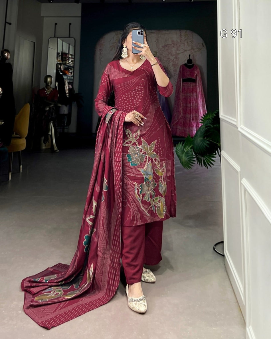 Woman wearing a maroon embroidered traditional outfit in a room.