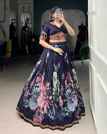 Woman wearing a dark blue floral lehenga in a room with mirrors and furniture.