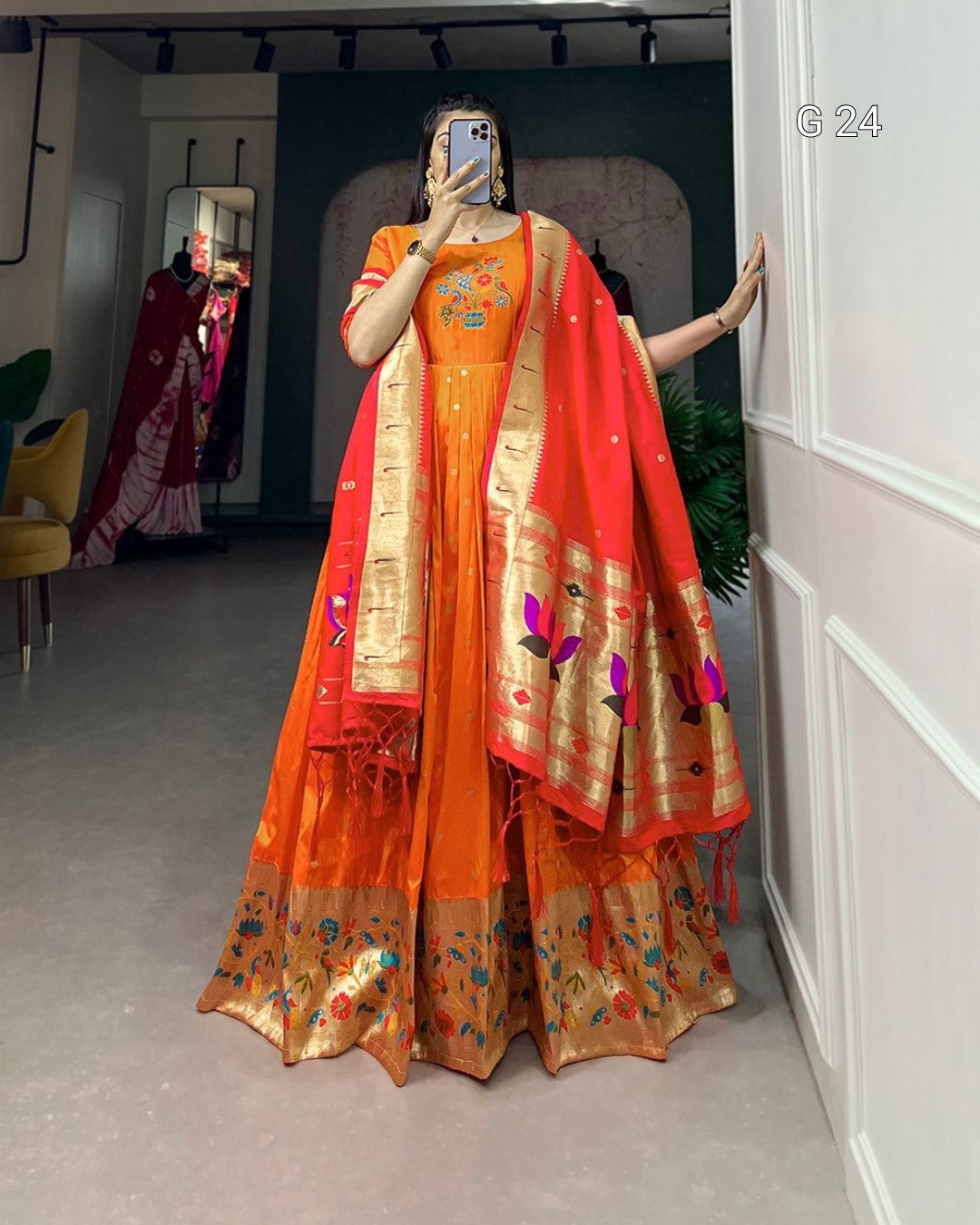 Person wearing an orange saree with a red border in a room.