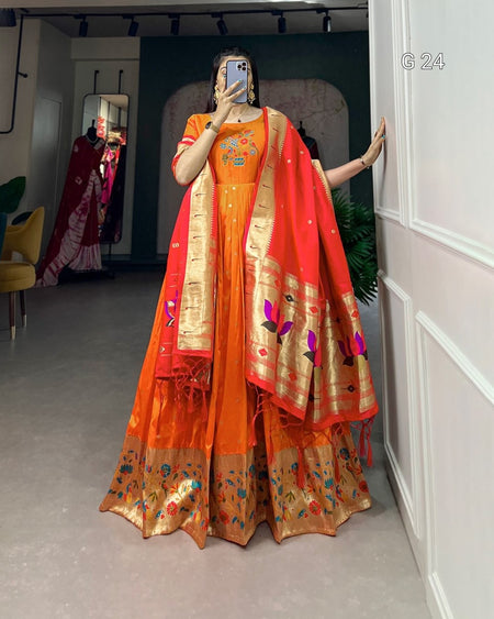 Person wearing an orange saree with a red border in a room.