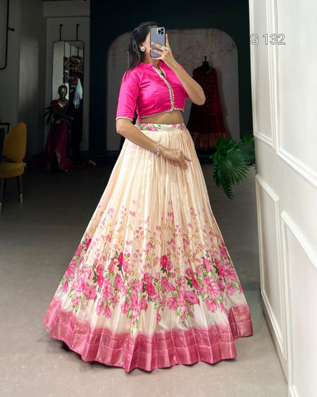 Woman wearing a pink blouse and floral skirt in a room with a mirror and plant.