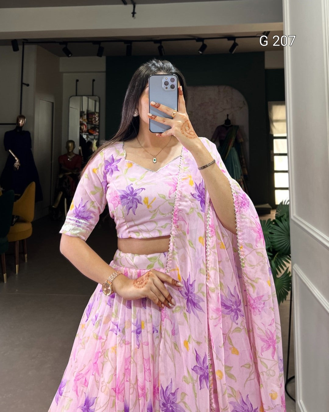 Woman wearing a floral pink and purple traditional outfit in a mirror selfie.