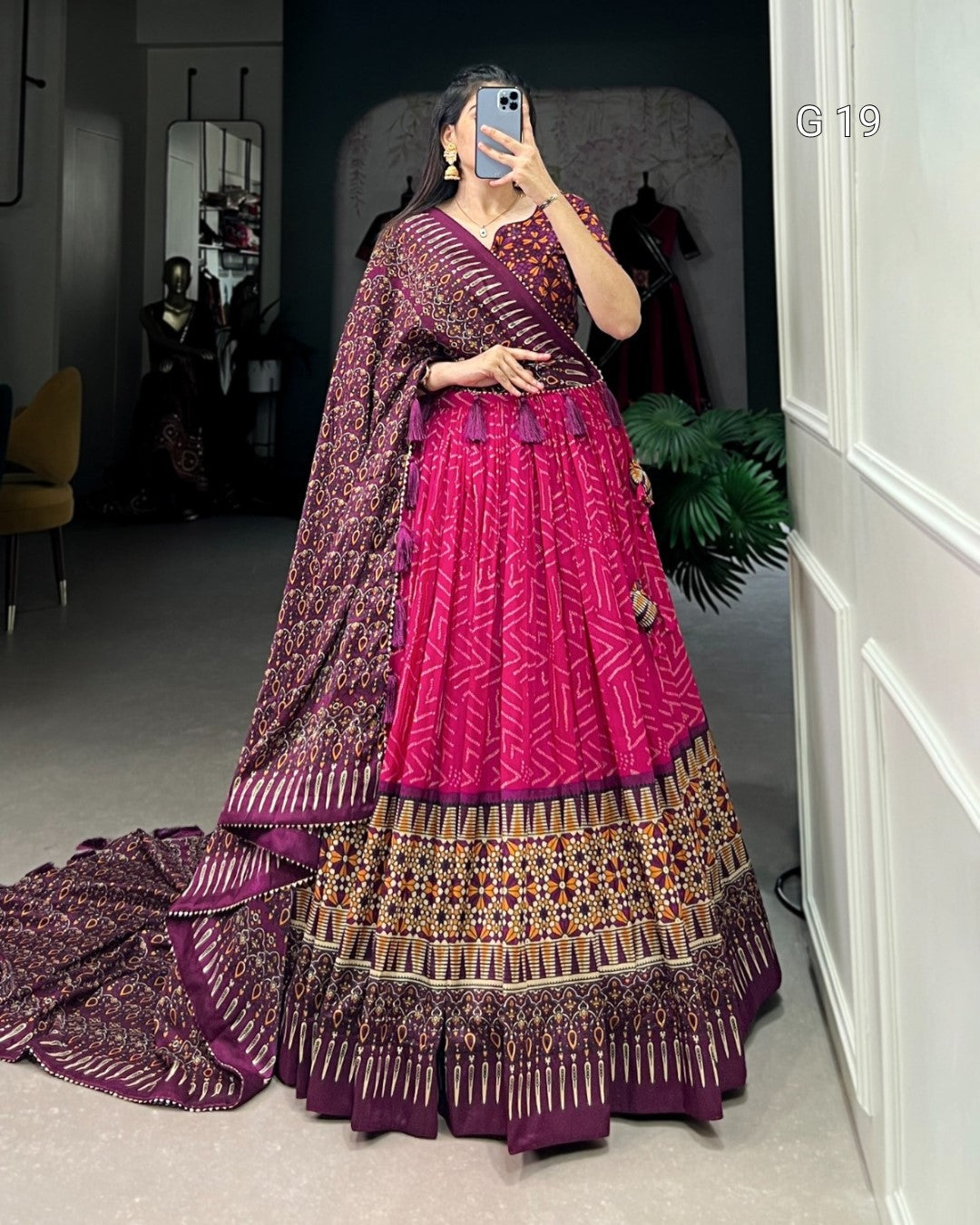 Person wearing a traditional outfit with a pink and purple color scheme, standing in a room.
