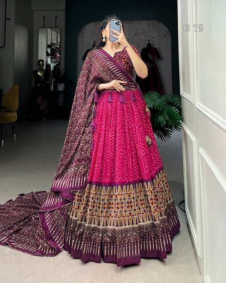 Person wearing a traditional outfit with a pink and purple color scheme, standing in a room.
