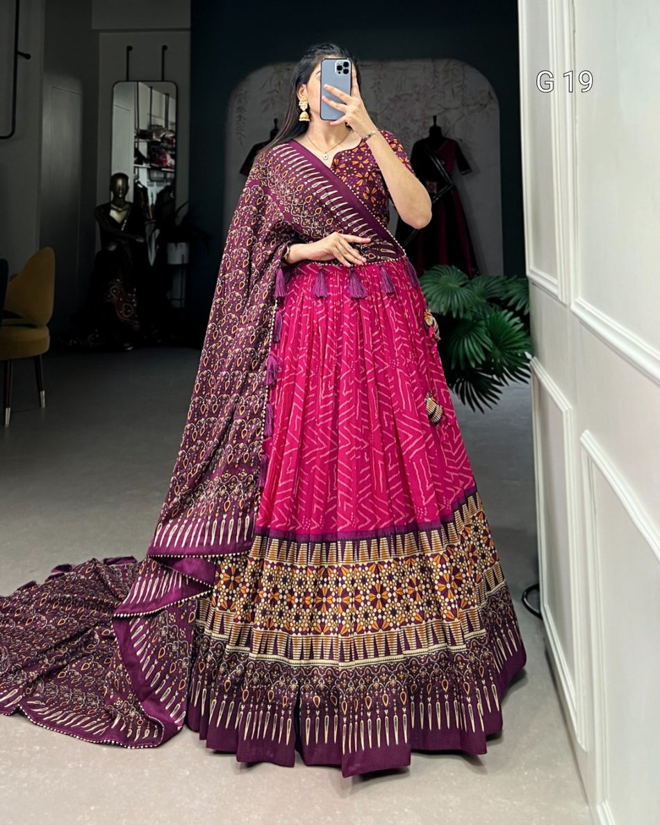 Person wearing a traditional outfit with a pink and purple color scheme, standing in a room.