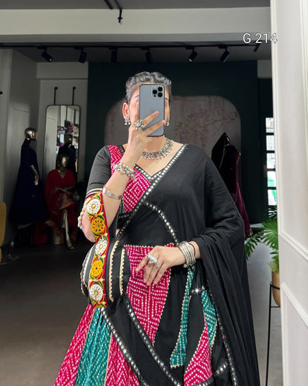 Person wearing a black saree with colorful patterns and jewelry in a store setting.