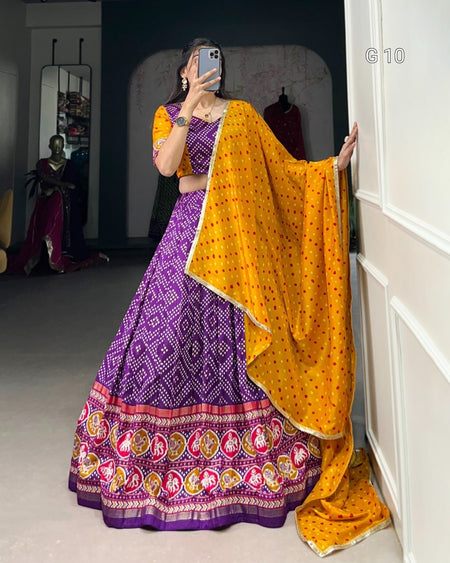 Person wearing a purple and yellow traditional outfit in a room.