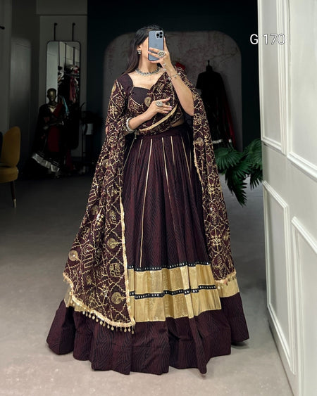 Woman wearing a traditional outfit with a dark purple and gold dress in a room.