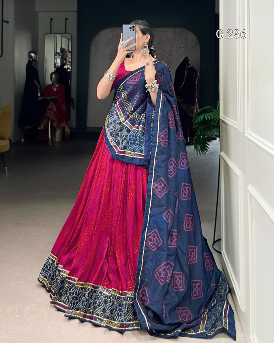 Woman wearing a traditional pink and blue saree in a room setting.