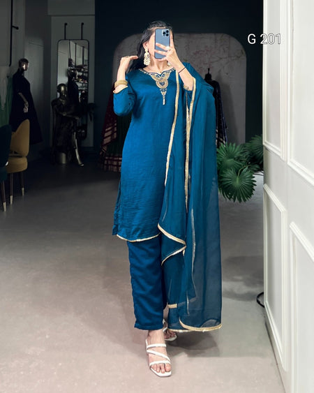 Person wearing a blue traditional outfit with a sheer dupatta in a room.