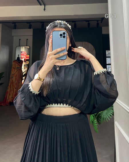 Person wearing a black outfit with sheer sleeves in a room.