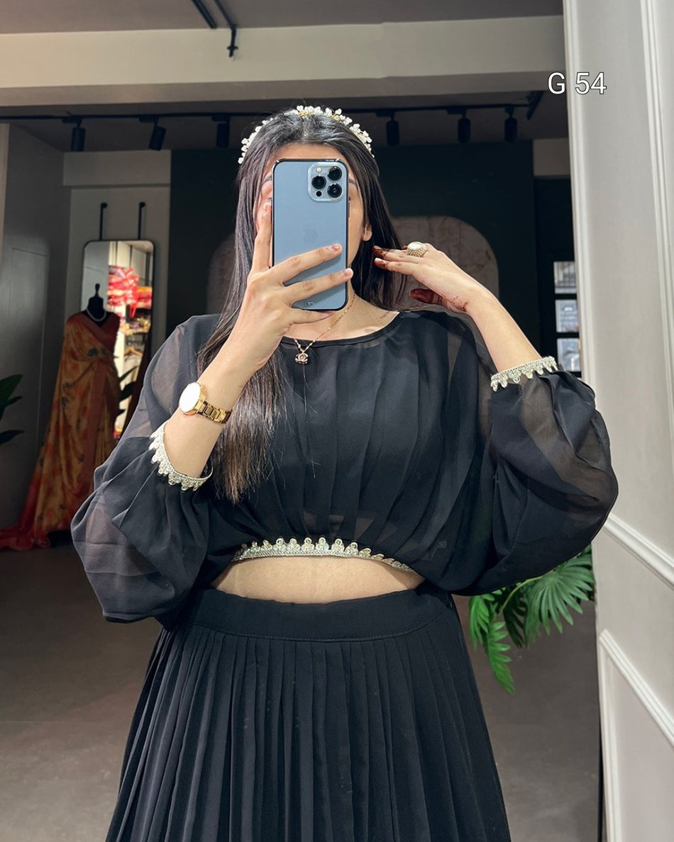 Person wearing a black outfit with sheer sleeves in a room.