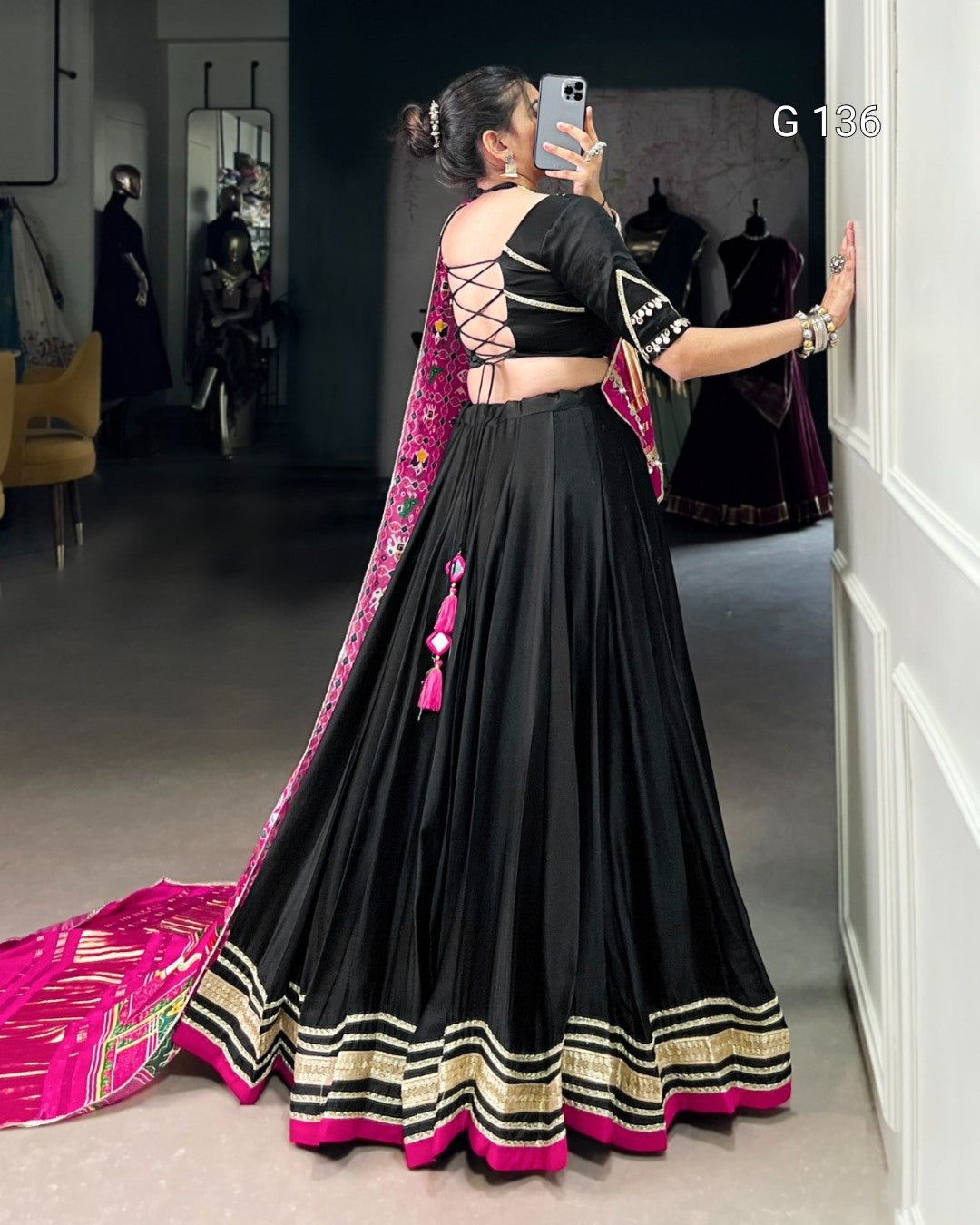 Woman in a black and pink traditional outfit taking a mirror selfie.