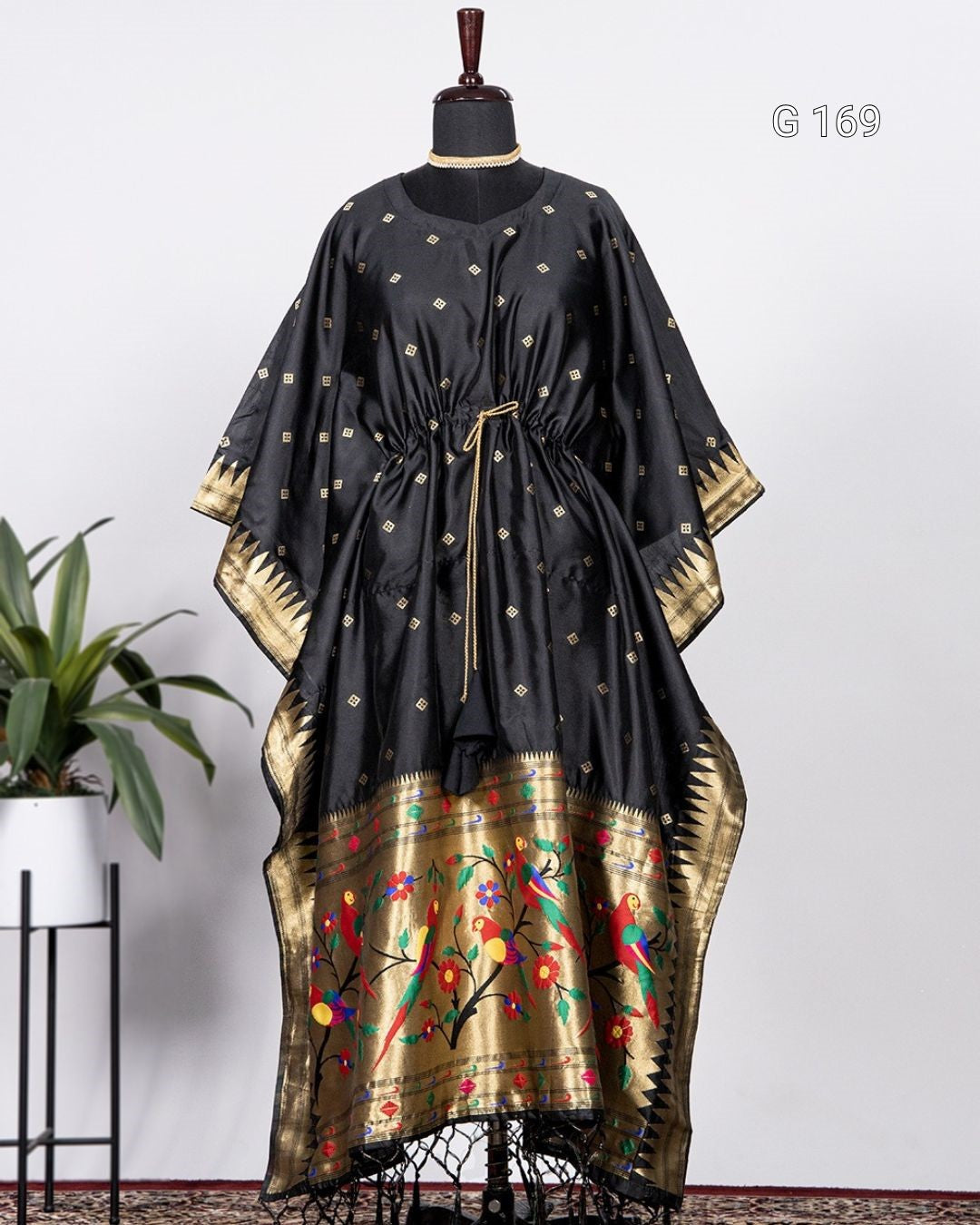 Black and gold traditional dress on a mannequin with a white background