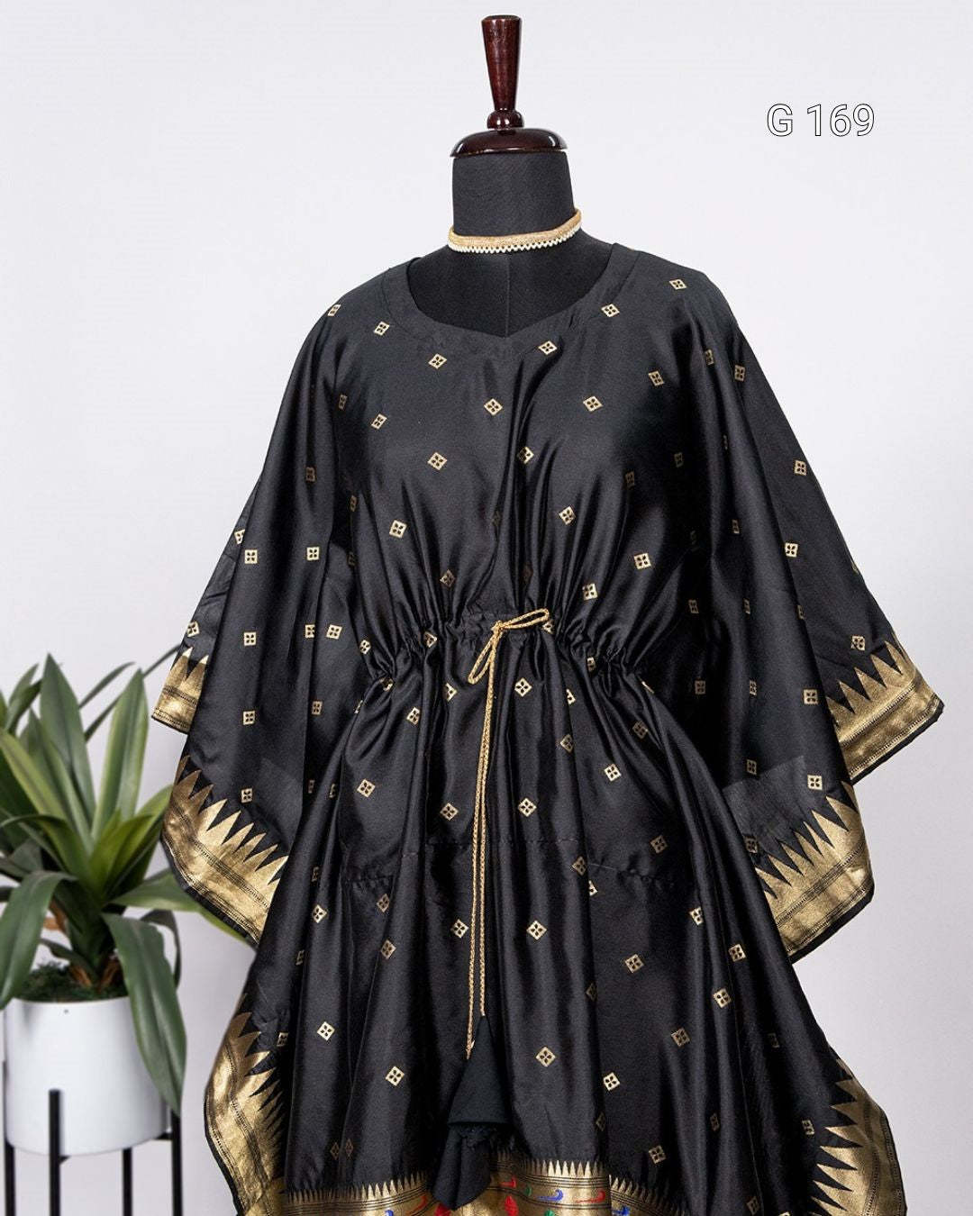 Black dress with gold patterns on a mannequin against a white background
