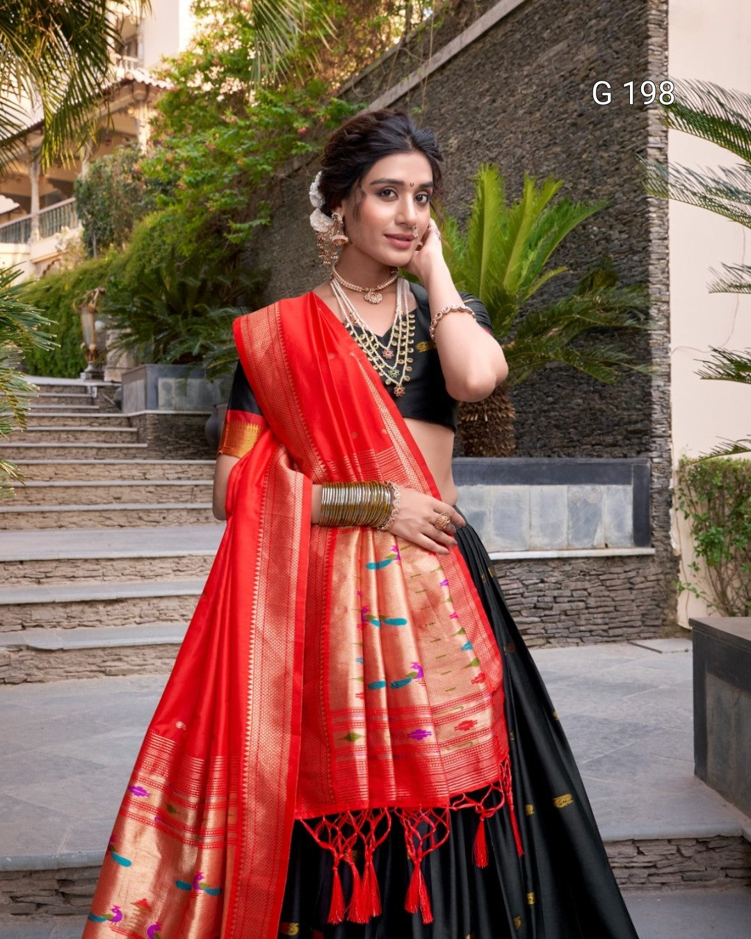 Woman wearing a red and black saree with a scenic background