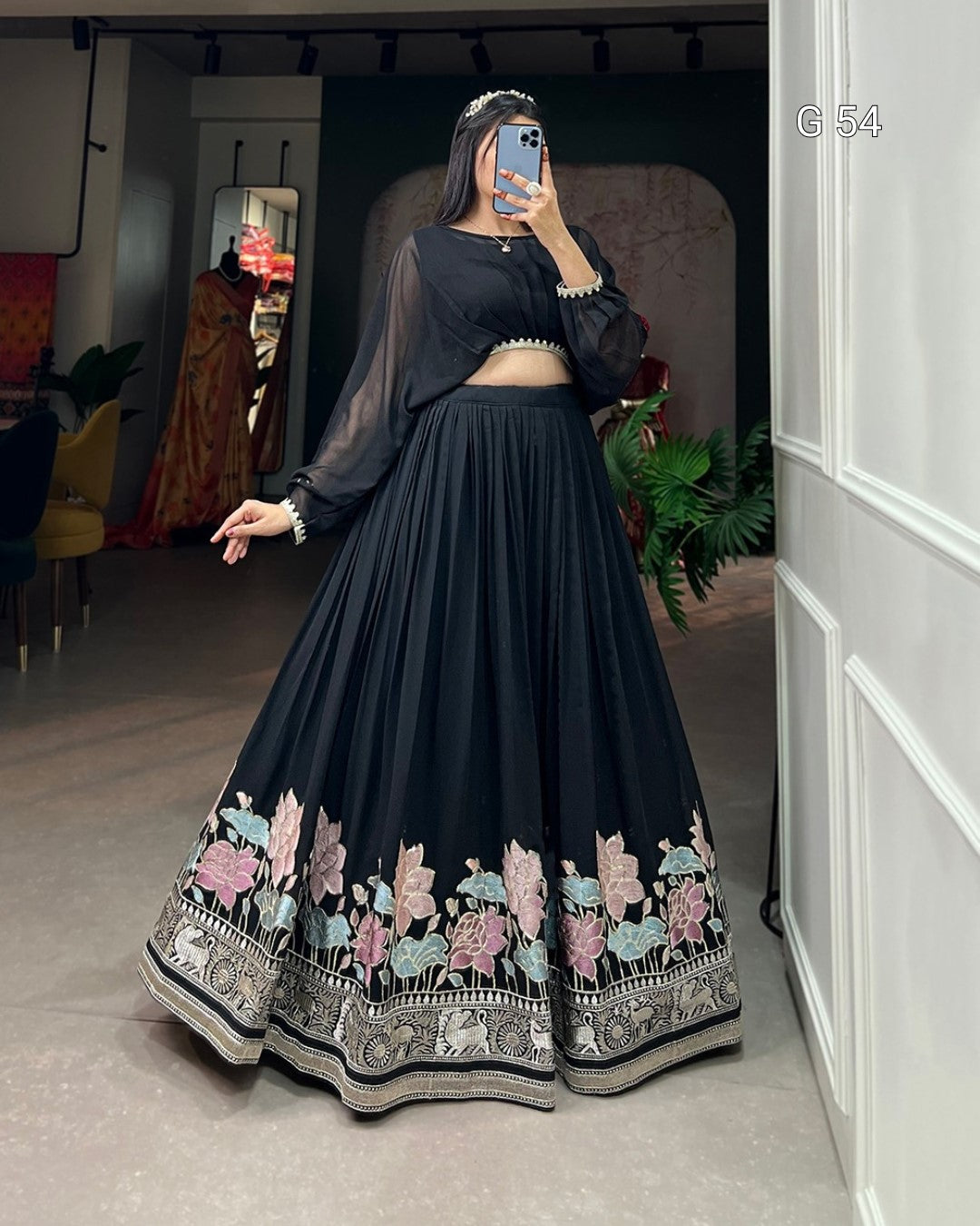 Person wearing a black embroidered traditional outfit in a room.