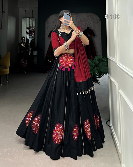 Woman wearing a black and red traditional outfit with floral patterns in a room.