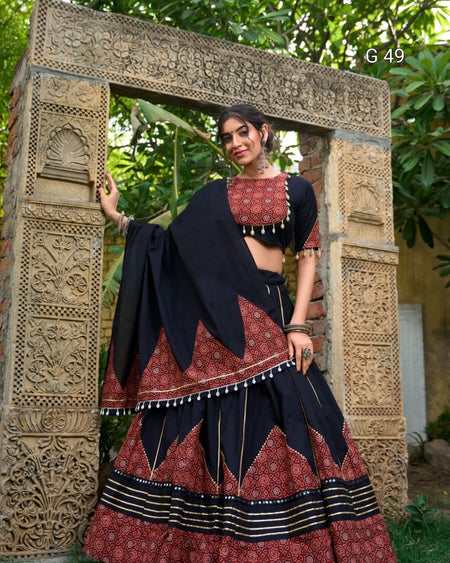 Woman in traditional attire standing in front of an ornate stone archway.