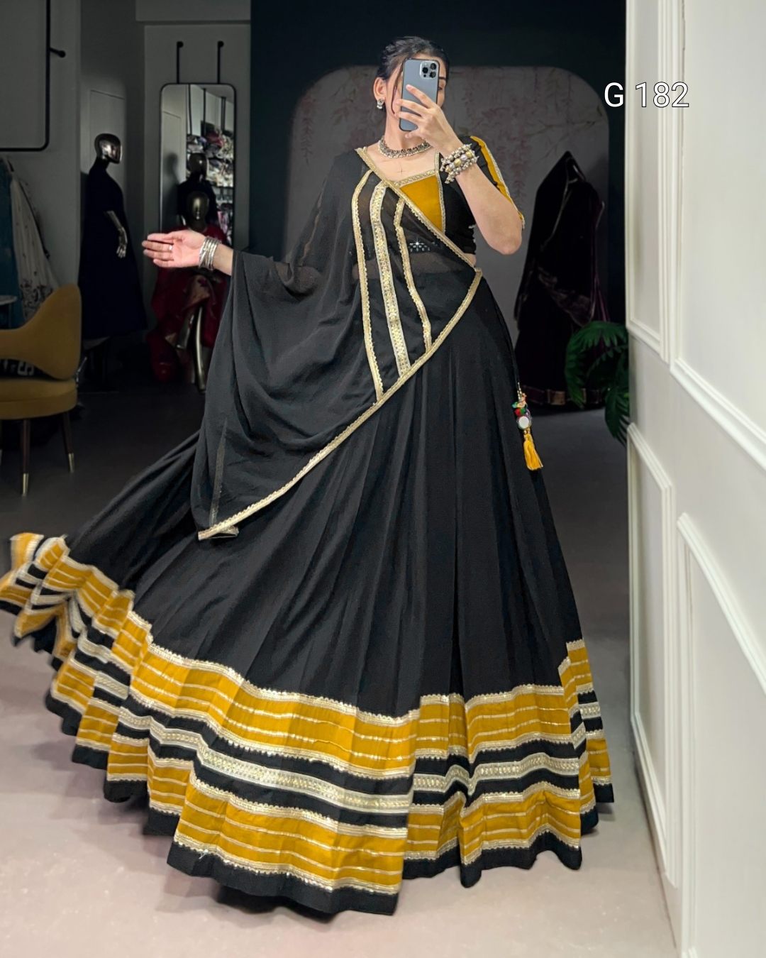 Person wearing a black and yellow dress with a long train in a room.