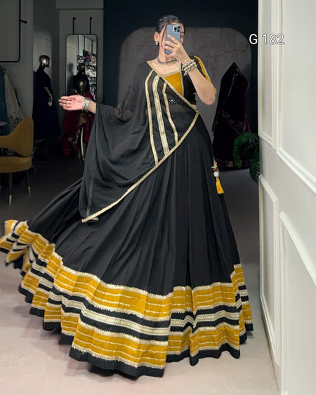 Person wearing a black and yellow dress with a long train in a room.
