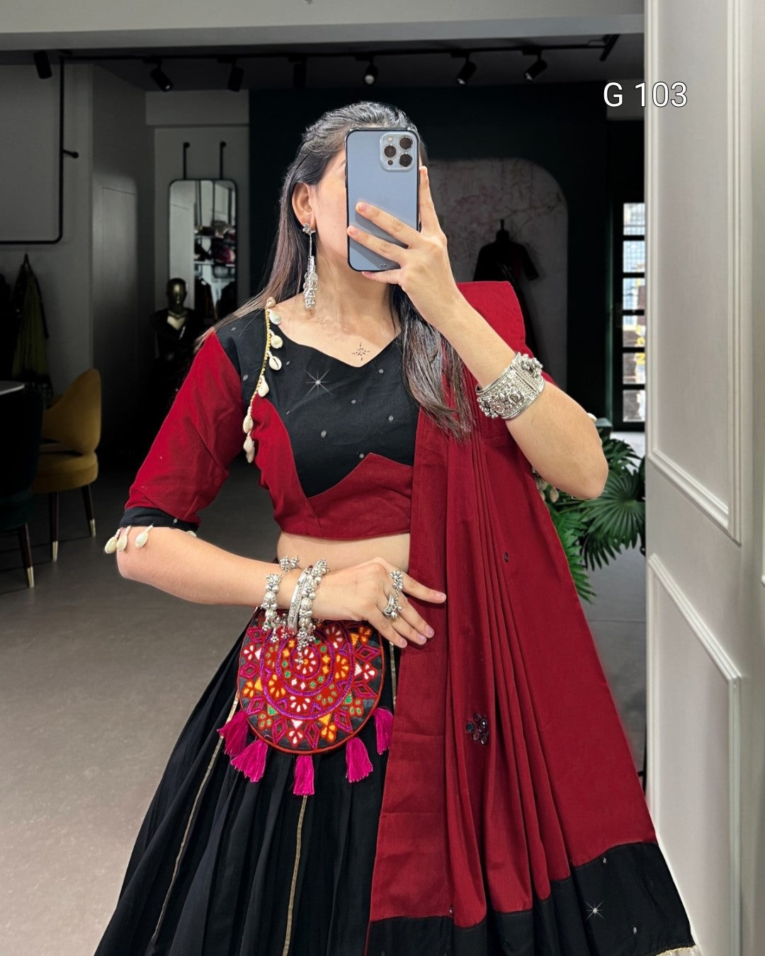 Person wearing a red and black traditional outfit with a colorful handbag indoors.