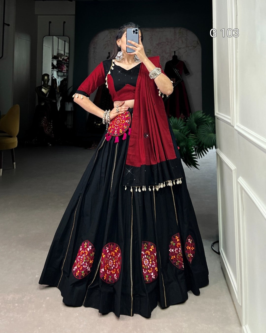 Woman wearing a black and red traditional outfit with floral patterns indoors.
