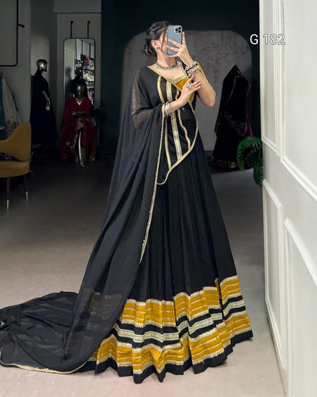 Woman wearing a black and yellow traditional outfit in a room with mirrors.