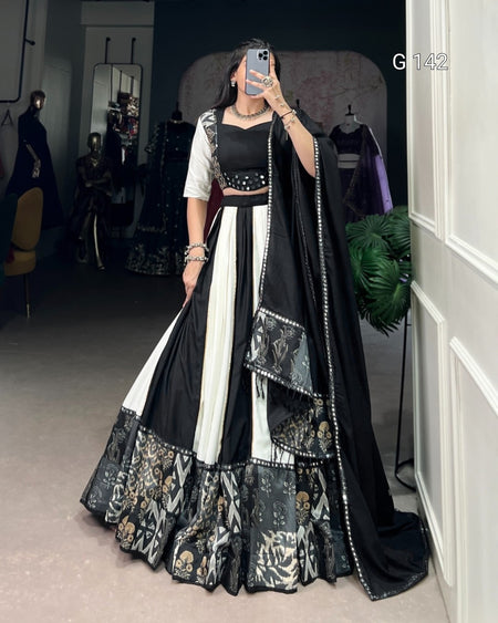 Person wearing a black and white traditional outfit with floral patterns in a room.