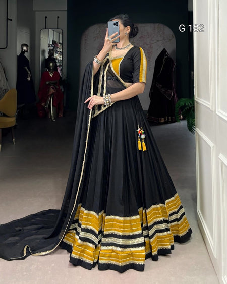 Woman wearing a black and yellow traditional outfit in a room.