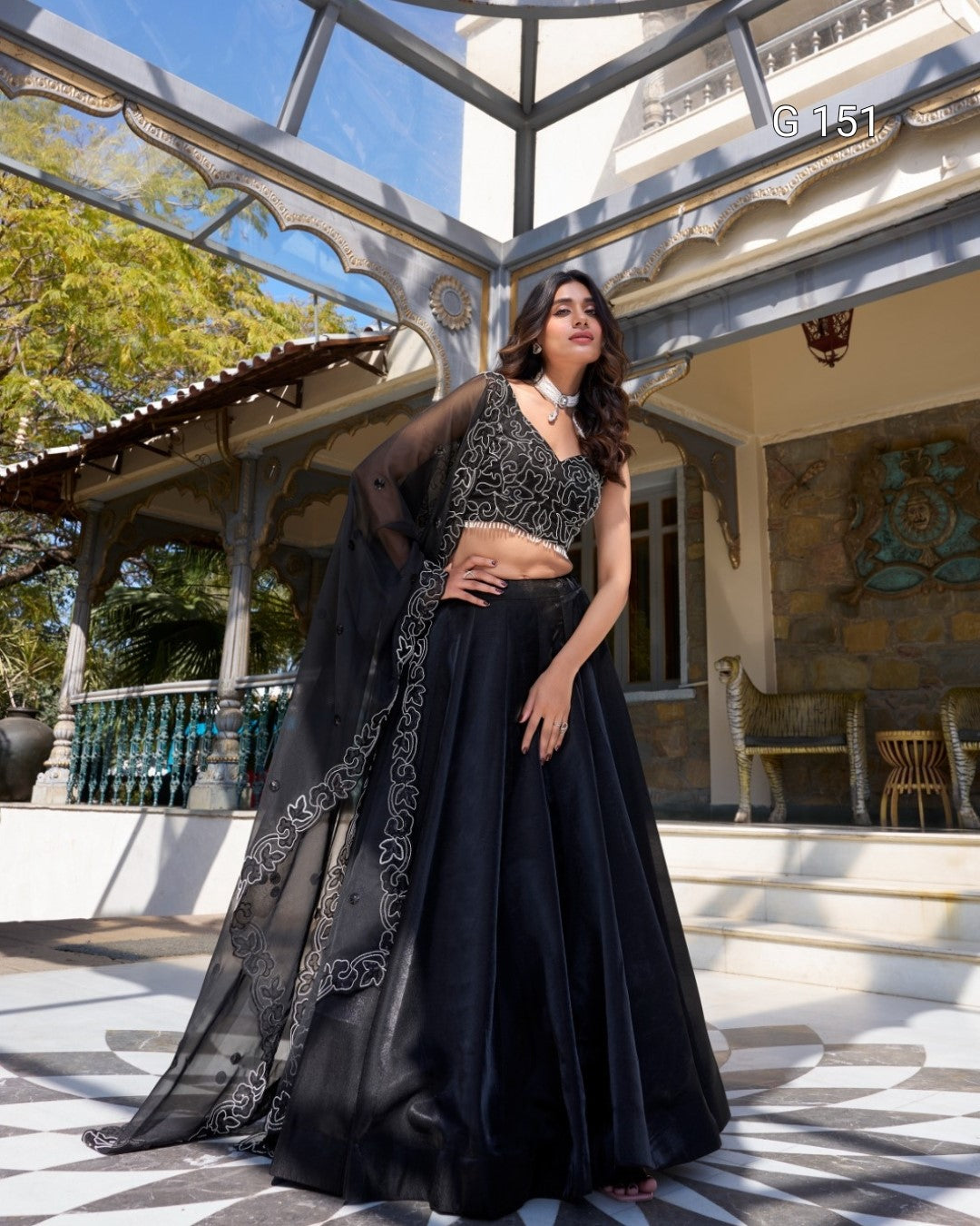 Woman in a black traditional outfit standing in an outdoor setting with architectural elements.