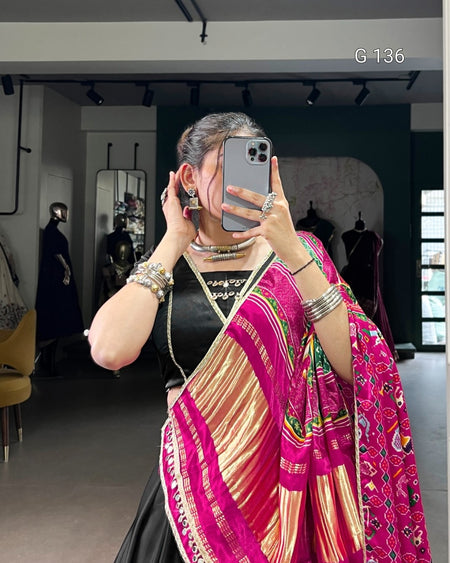 Woman taking a mirror selfie wearing a colorful saree in a store setting.