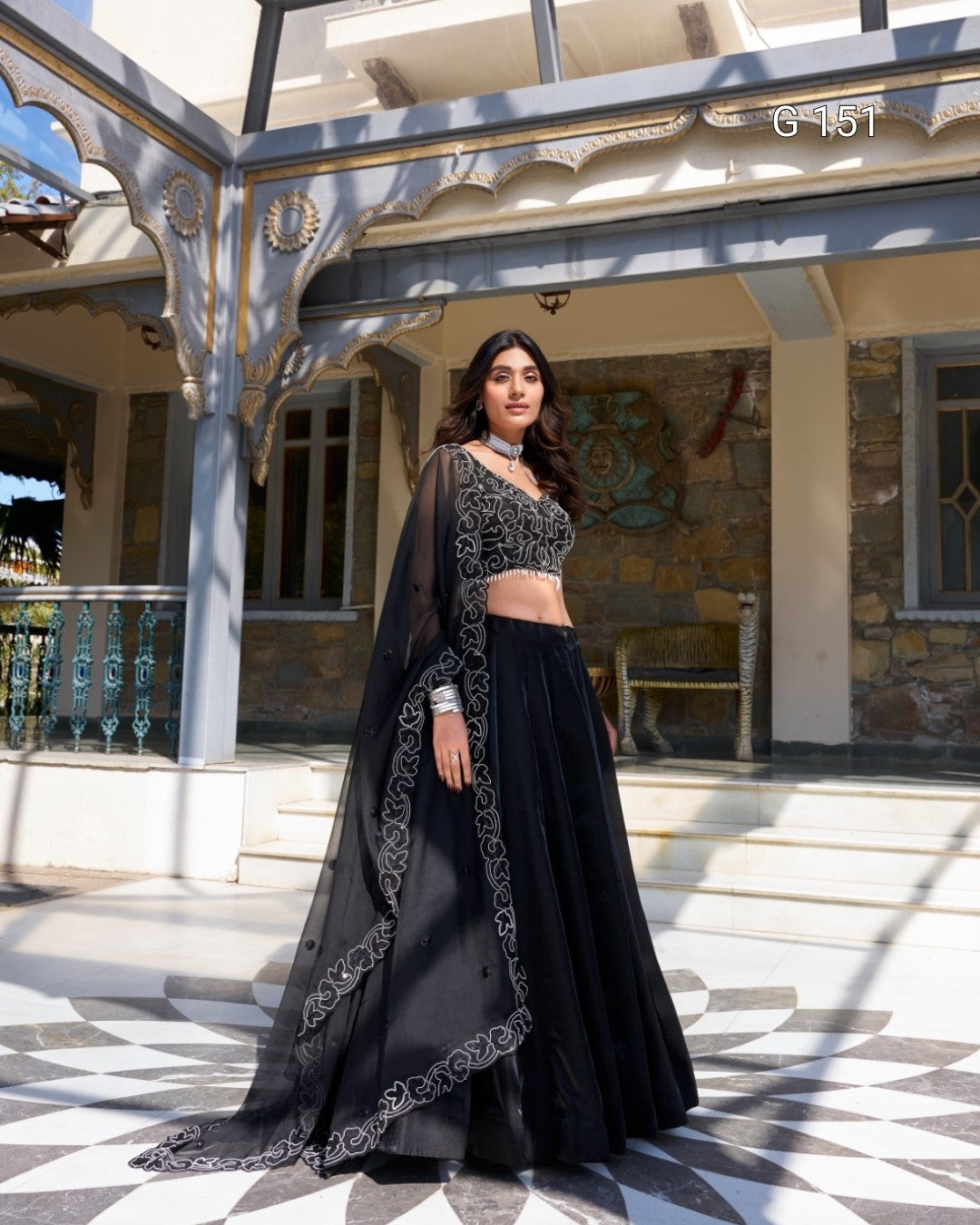 Woman in a black traditional outfit standing in front of a building with decorative architecture.