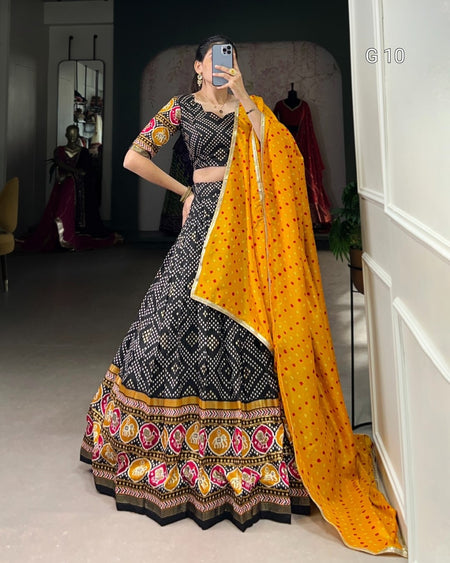 Woman in a traditional black and yellow outfit with a patterned dupatta taking a mirror selfie.