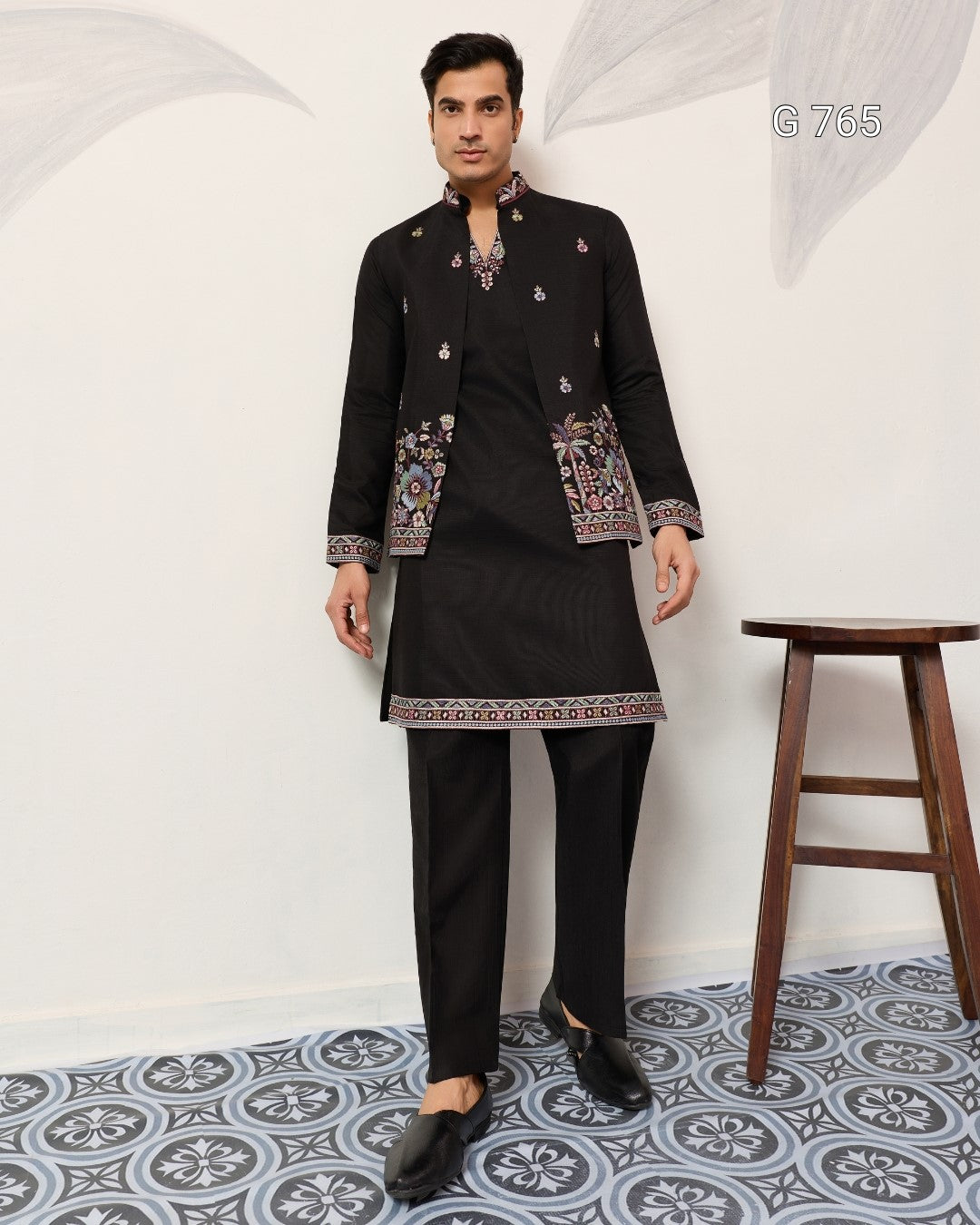 Man wearing a black traditional outfit with intricate patterns on a white background