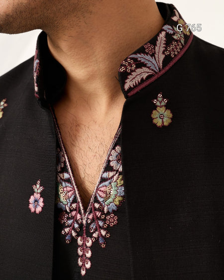 Close-up of a black embroidered shirt with floral patterns on a plain background