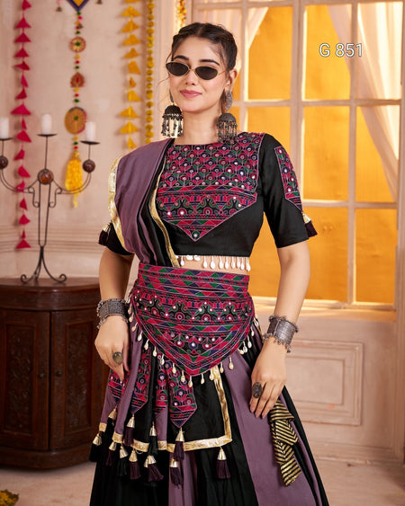 Woman wearing a traditional outfit with intricate patterns in a decorated room.