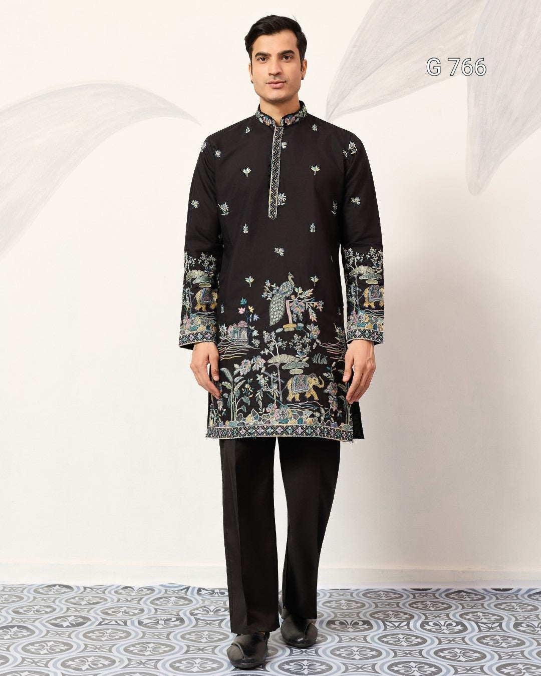 Man wearing a black embroidered kurta with pants on a white background