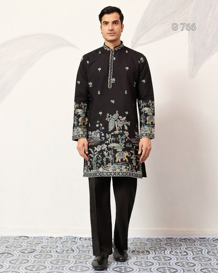 Man wearing a black embroidered kurta with pants on a white background