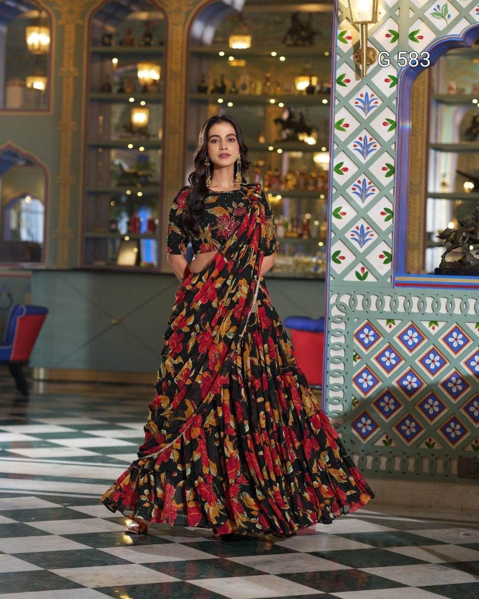 A woman models a black floral printed maxi dress with a matching printed blouse in an ornate, traditional Indian interior with patterned walls and a checkered floor.