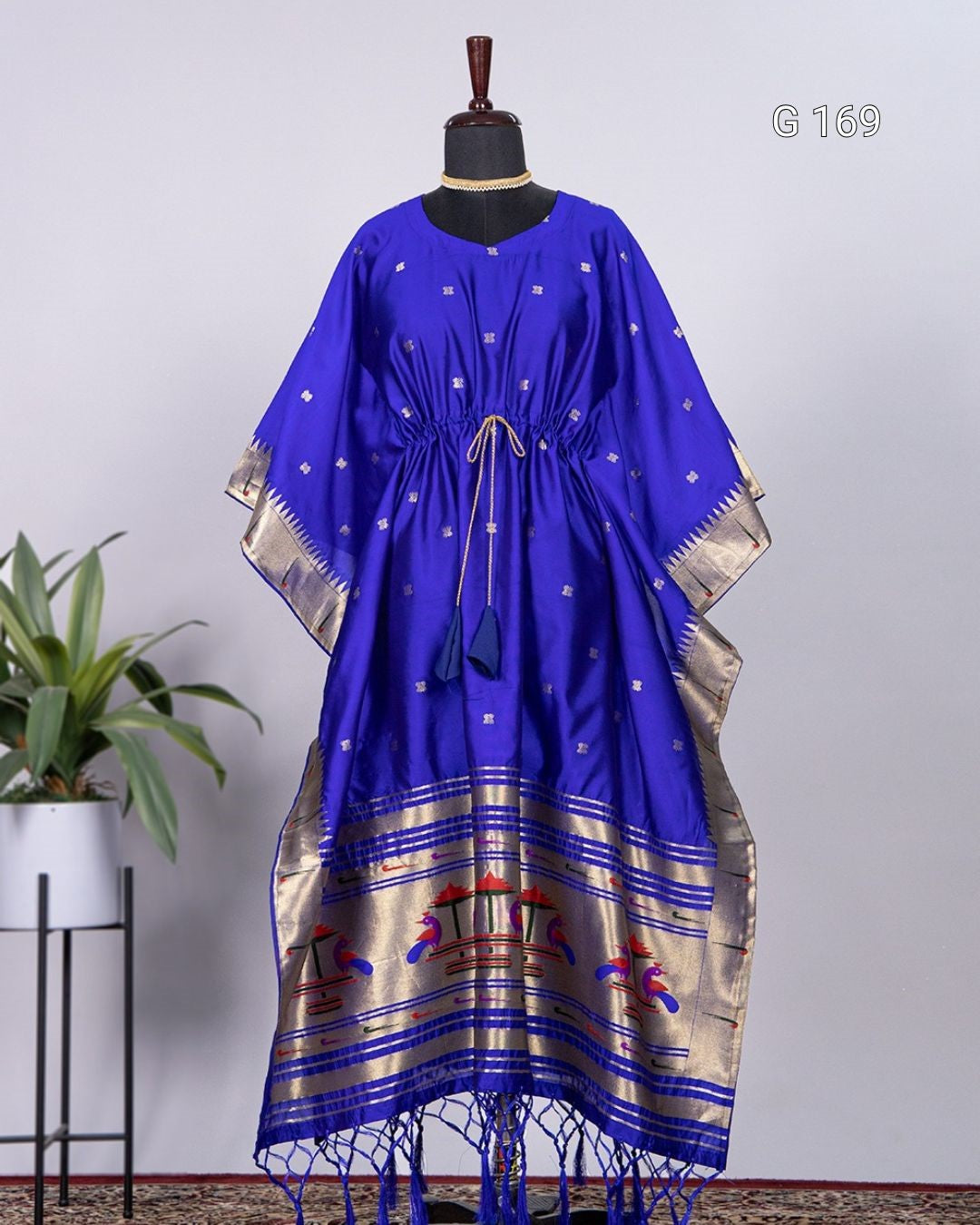 Blue dress with gold patterns on a mannequin against a light gray background