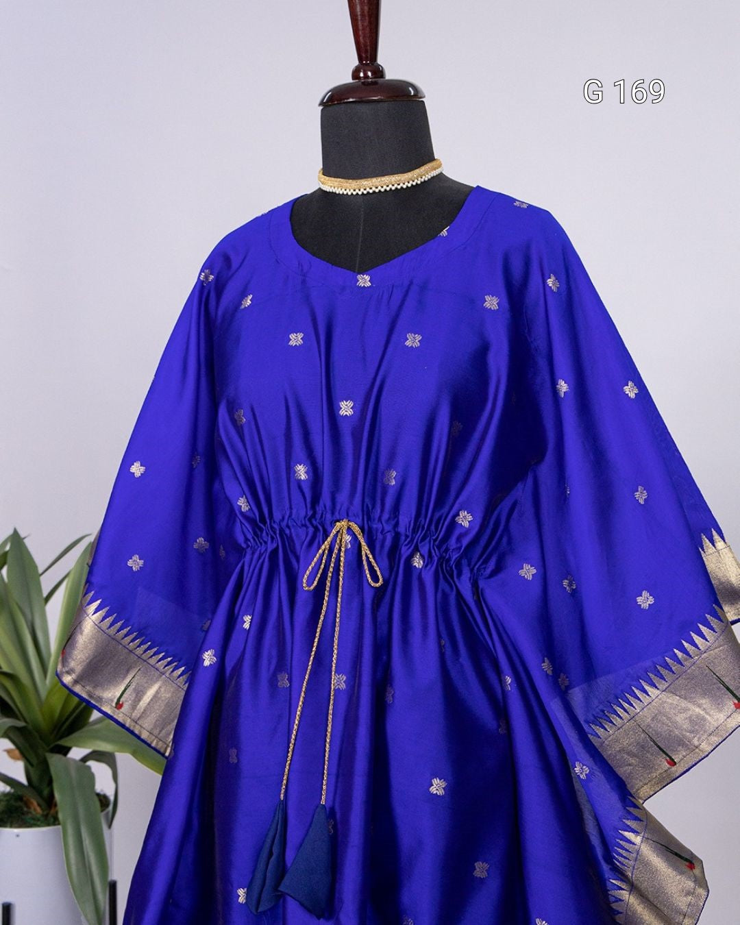 Blue dress with gold patterns on a mannequin against a white background