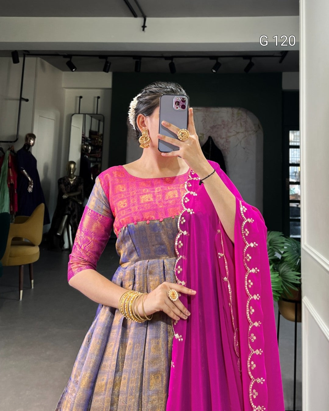 Person wearing a pink and purple traditional outfit with gold jewelry in a store setting.