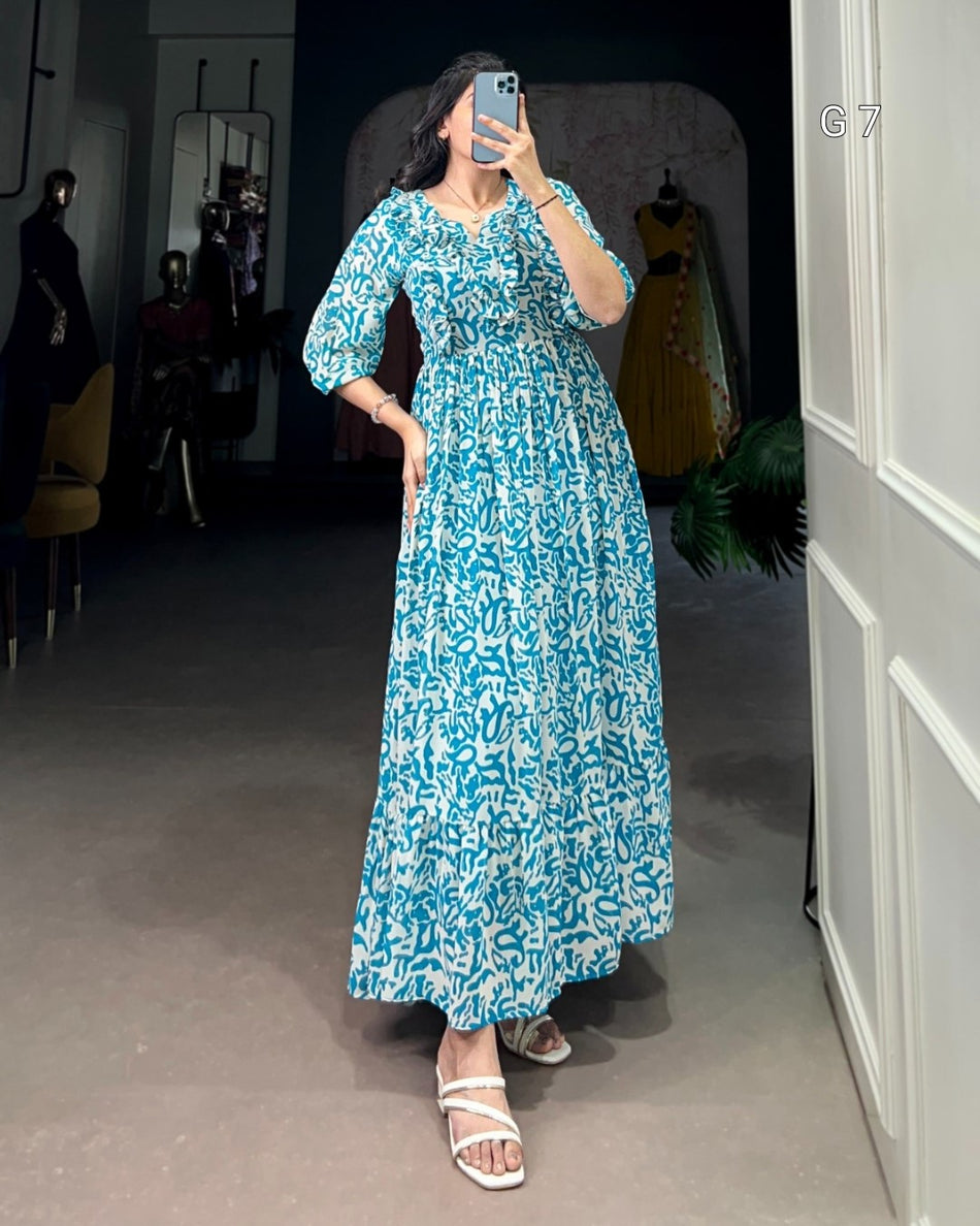 Woman in a blue floral dress taking a mirror selfie in a room with gray walls and a white door.
