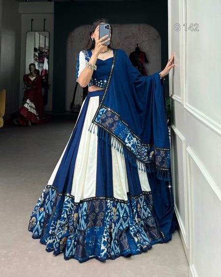 Person wearing a blue and white traditional outfit with a matching dupatta in a room.