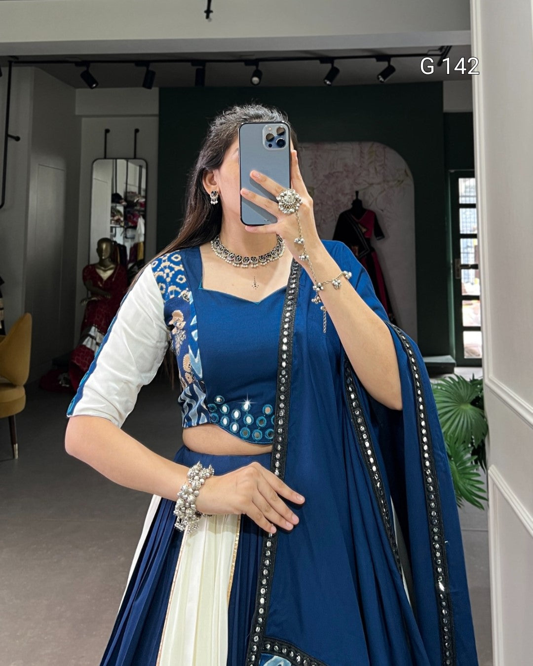 Person wearing a blue traditional outfit with white accents, standing in a room.