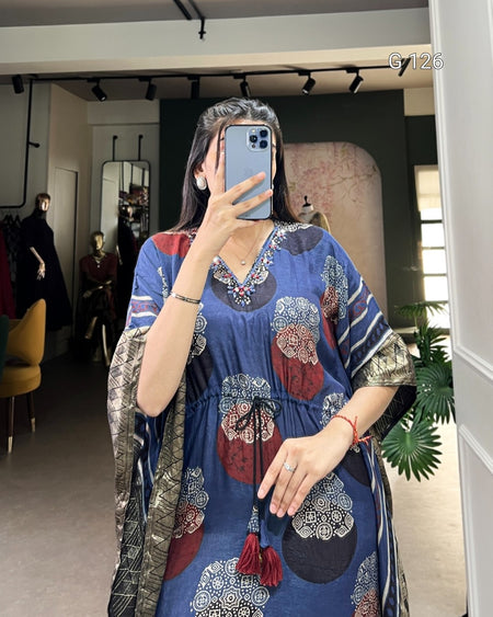 Person wearing a blue dress with floral patterns in a room.